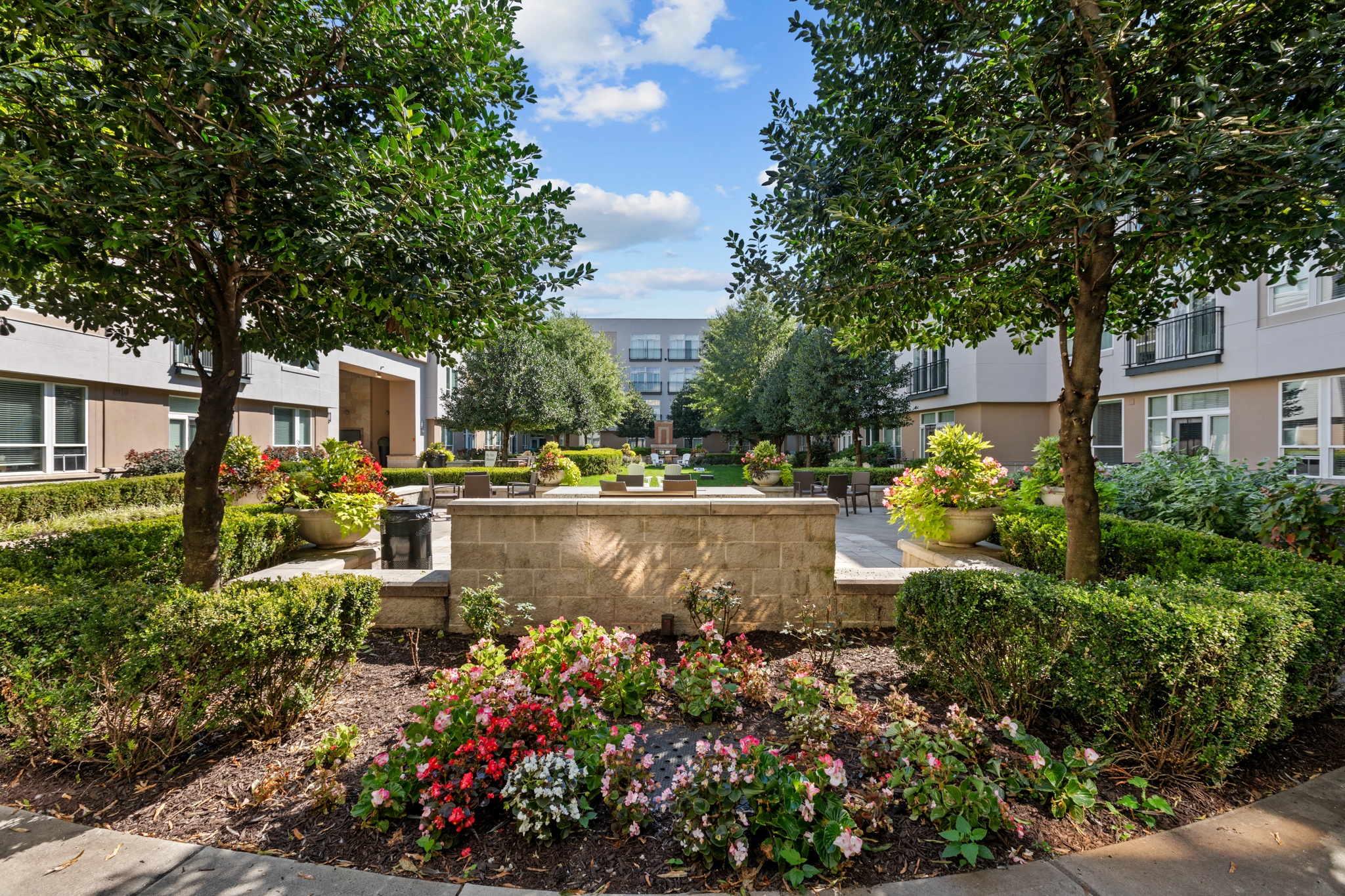 a courtyard with trees and flowers and a fountain